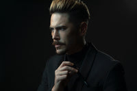Man adjusting his collar against a dark background